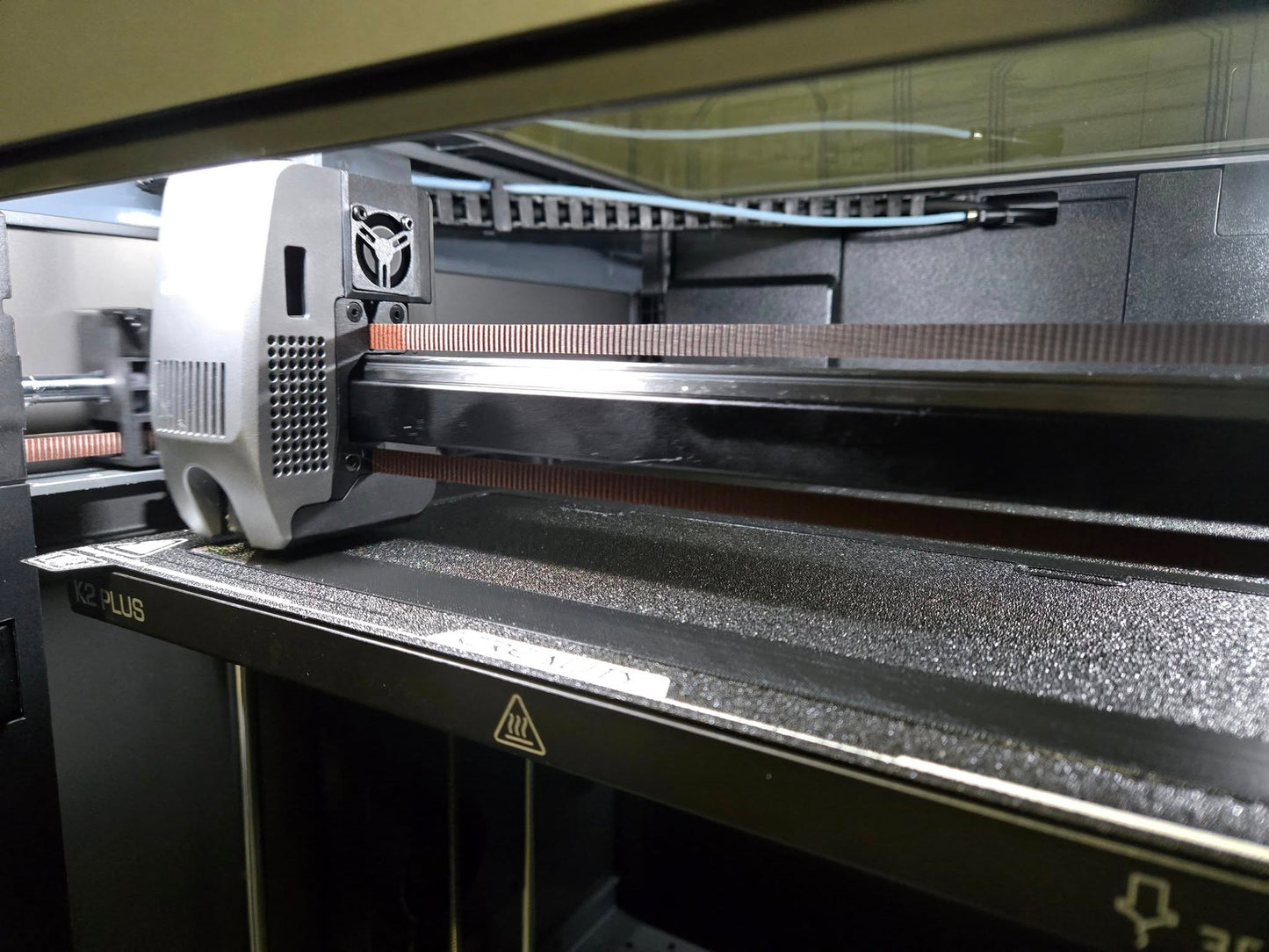 3D printer in operation with a detailed view of the print head and bed.