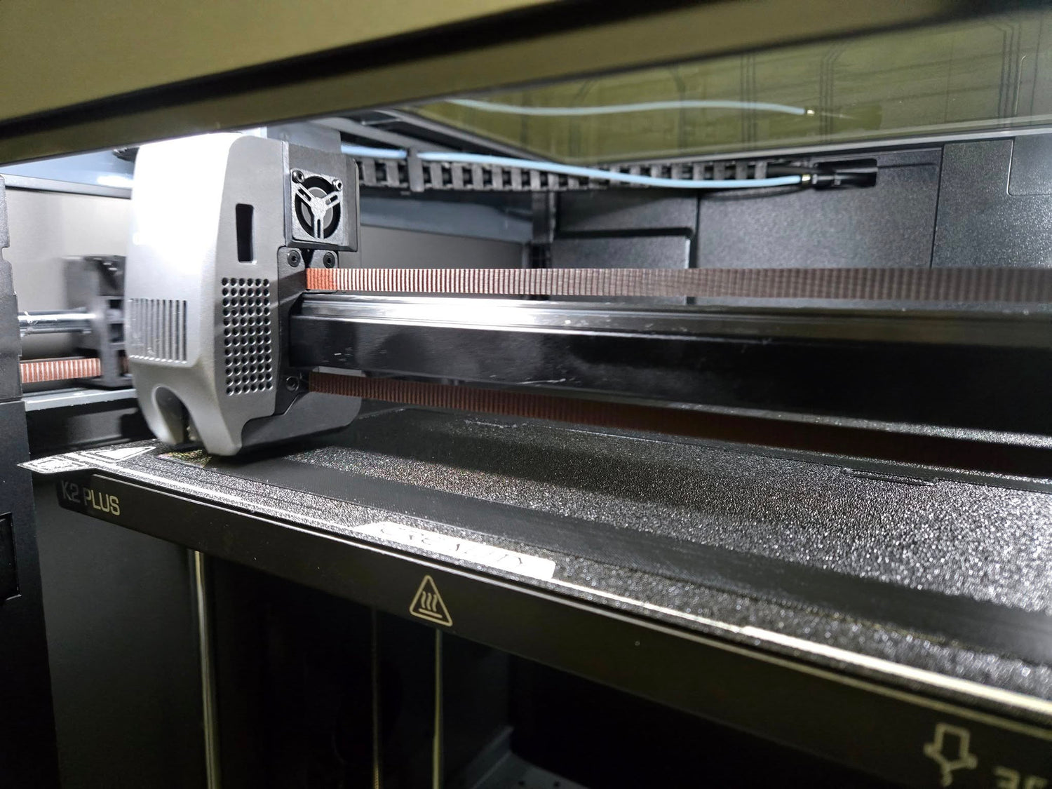 3D printer in operation with a detailed view of the print head and bed.