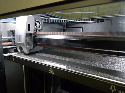 3D printer in operation with a detailed view of the print head and bed.